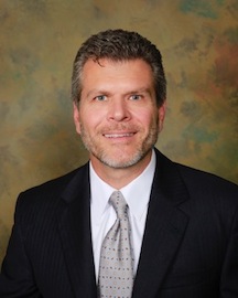 Joseph Gauta MD in professional headshot wearing dark suit and gray tie